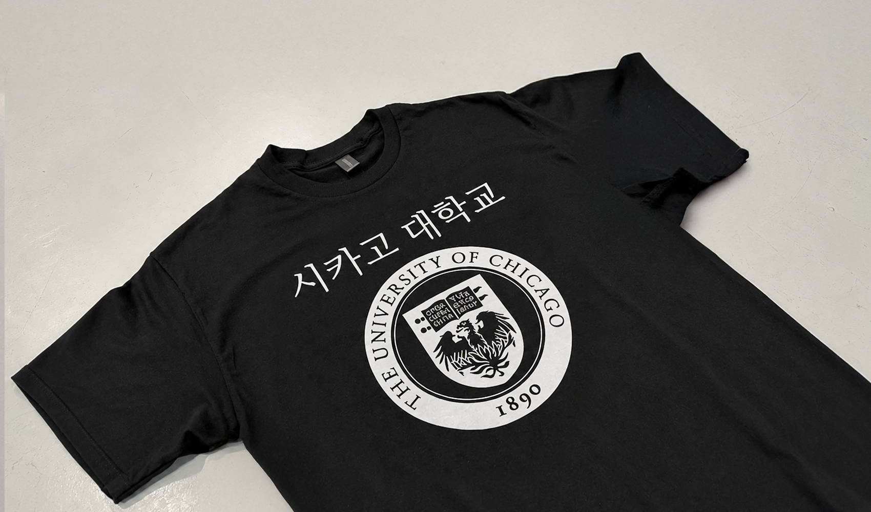 마플 커스텀 반팔 티셔츠 – 검은색 티셔츠 전면에 시카고대학교 영문명과 문장을 흰색으로 크게 인쇄해 펼쳐 놓은 이미지