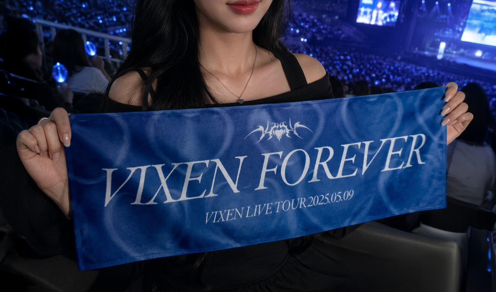마플 롱 슬로건 – VIXEN FOREVER 문구와 공연 날짜를 흰색으로 인쇄한 파란색 슬로건을 여성이 콘서트 좌석에서 양손으로 펼쳐 든 이미지