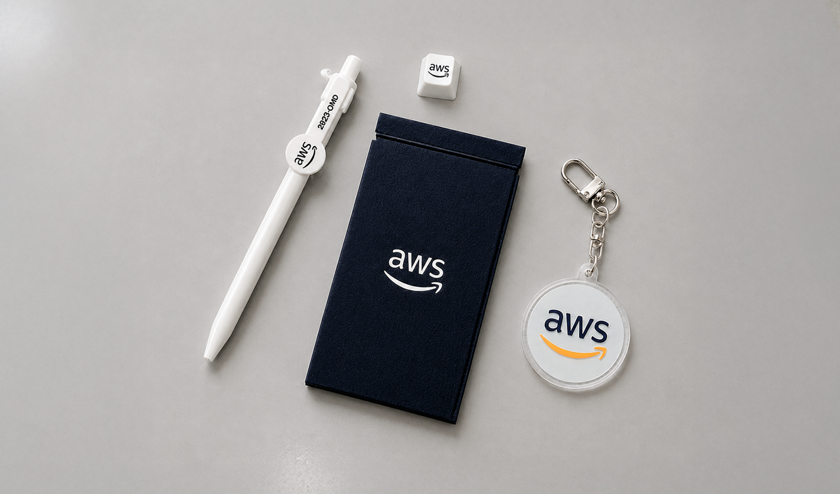 마플 AWS 기업 굿즈 – AWS 로고를 적용한 펜, 카드지갑, 투명 아크릴 키링과 키캡으로 구성한 웰컴키트 이미지