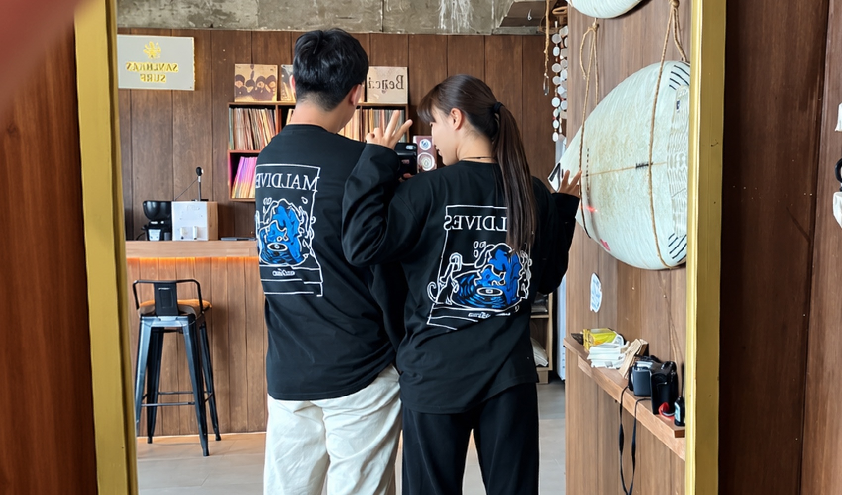 마플 긴팔 티셔츠 제작 - 등판에 파란색 캐릭터와 흰색 영문, 사각형 테두리를 넣어 커플로 맞춰 입은 검정 긴팔 티셔츠