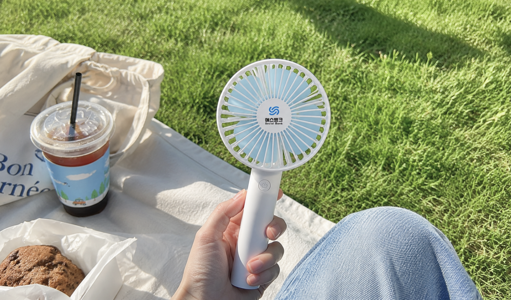 마플 휴대용 선풍기 금융사 로고를 인쇄한 화이트 선풍기를 야외 피크닉에서 한 손으로 들고 있는 이미지