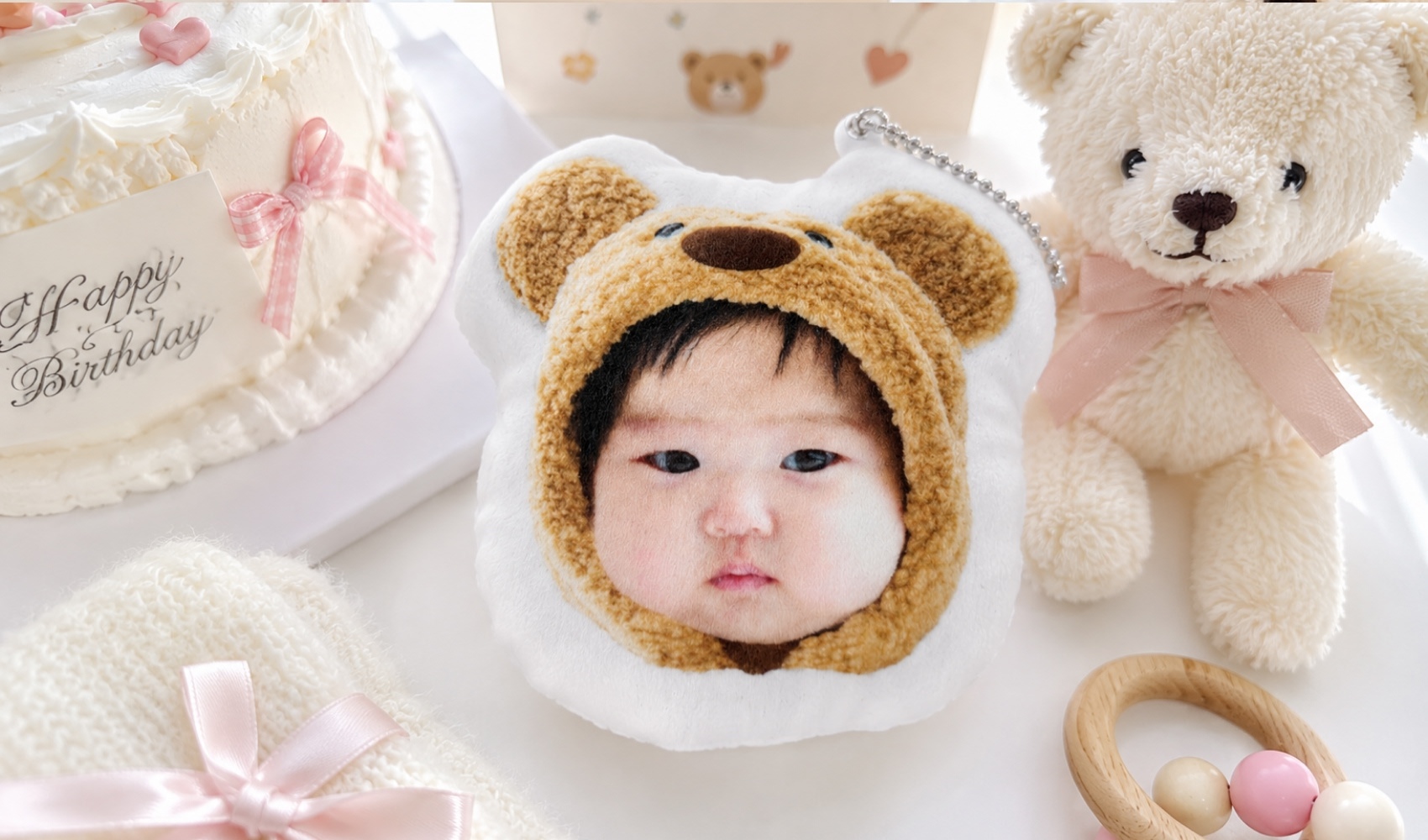 마플 커스텀 봉제 인형 키링 - 아기 사진을 인쇄해 제작한 곰돌이 모양 봉제 인형 키링을 생일 소품과 함께 배치한 이미지