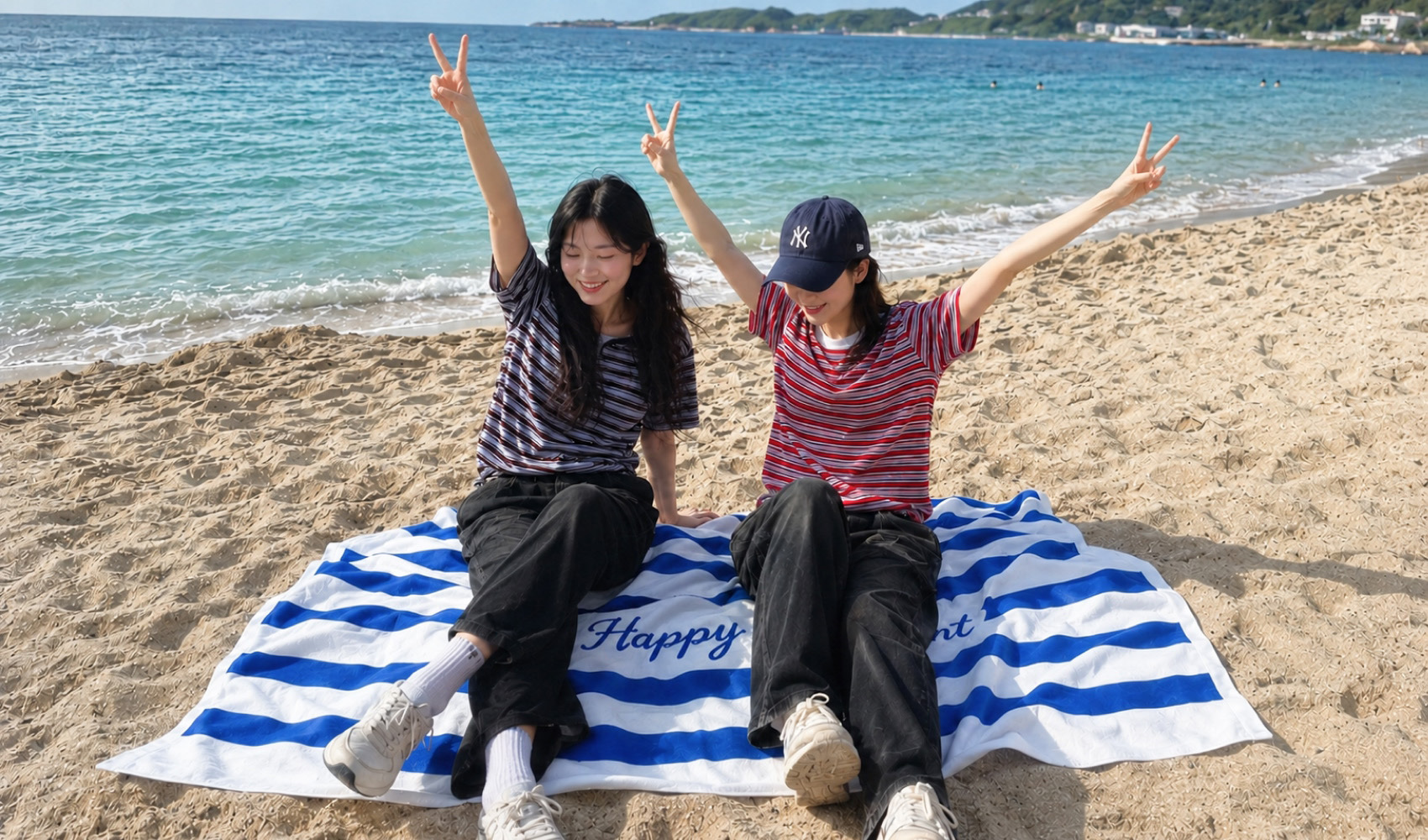마플 비치타올 블루 스트라이프 패턴과 문구를 풀 컬러 인쇄한 비치타올을 해변 모래사장에 깔고 2인이 앉은 이미지