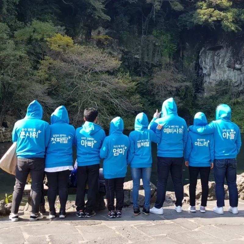 마플 가족 단체 후드집업 – 가족 관계명이 등판에 프린팅된 블루 후드집업을 맞춰 입은 가족들의 야외 뒷모습 이미지